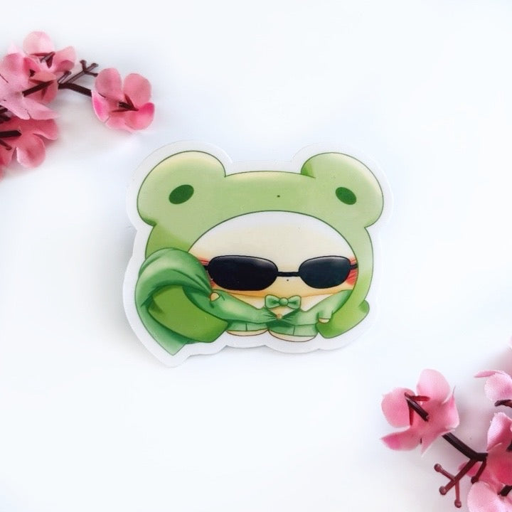Cartoon character that is a chick with a frog costume wearing a green suit, green bow tie, sunglasses and holding a green jacket on a white background with pink flowers.