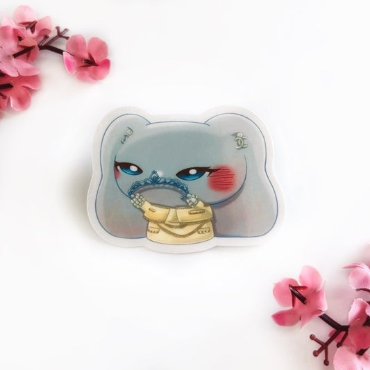 Sticker of an elephant-bunny hybrid wearing a classy, beige dress with a matching beige jacket, holding a silver crown on a white background with pink flowers. They are wearing Chanel earrings and pearl bracelets.