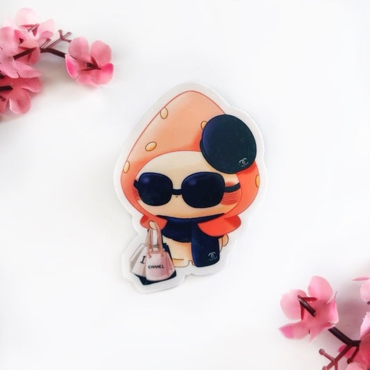 A picture of a bunny in a red strawberry hat wearing a dark blue Chanel scarf, sunglasses, and beret. She is holding Chanel, Dior, and Louis Vuitton shopping bags. The background is white with pink flowers.